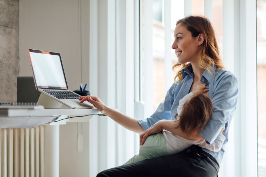 Woman working on laptop computer while breastfeeding her child